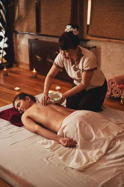 Thai woman smearing massage cream on lady back — Stock Photo, Image