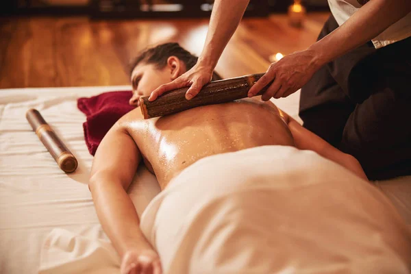 Massagista operando com bar de massagem em cima da mulher de volta — Fotografia de Stock