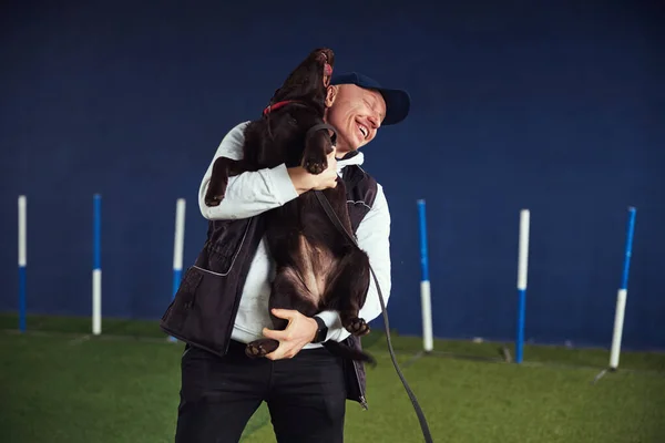 Feliz instructor y un Chocolate Labrador Retriever en sus brazos — Foto de Stock