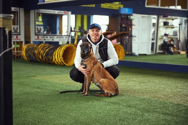 Instructor posando para la cámara con un perro adulto tranquilo — Foto de Stock