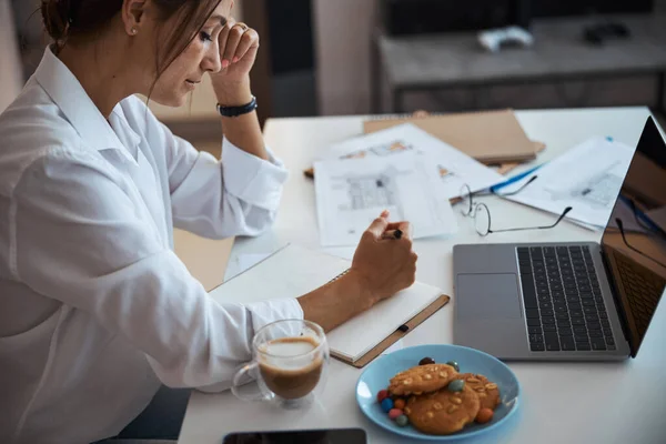 Bella donna che scrive nel taccuino e utilizza il computer portatile al lavoro — Foto Stock