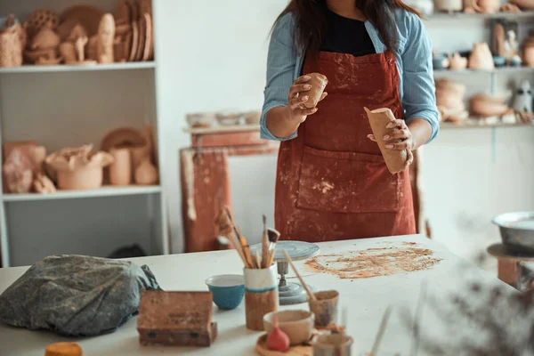 Femme céramiste dans un tablier travaillant dans un atelier de poterie — Photo