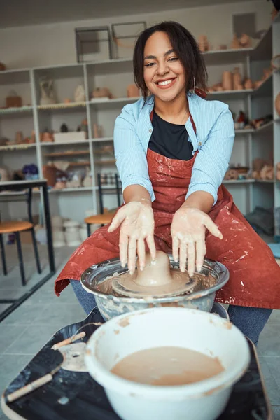 Femme joyeuse montrant les mains dans l'argile après avoir fait de la poterie — Photo