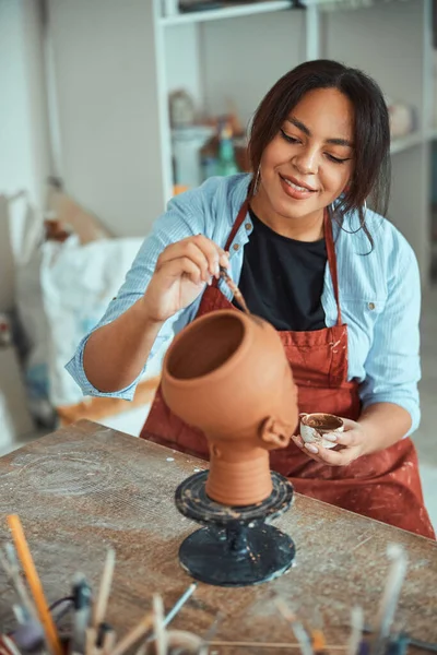 Belle jeune femme peignant des poteries en atelier — Photo