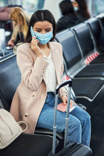 空港で携帯電話で話す医療マスクのエレガントな女性 — ストック写真