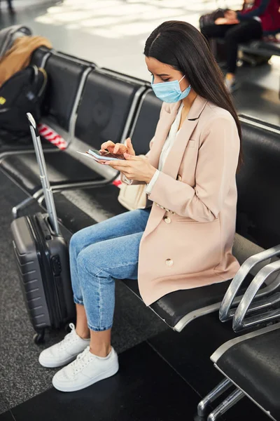 空港で携帯電話を使用して医療用マスクのエレガントな女性 — ストック写真