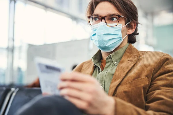 Orvosi maszkos férfi várja a repülést a repülőtéren. — Stock Fotó