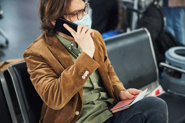 空港で携帯電話で話す医療マスクのスタイリッシュな男 — ストック写真