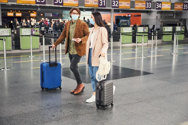 Jovem e mulher em máscaras médicas andando no aeroporto — Fotografia de Stock