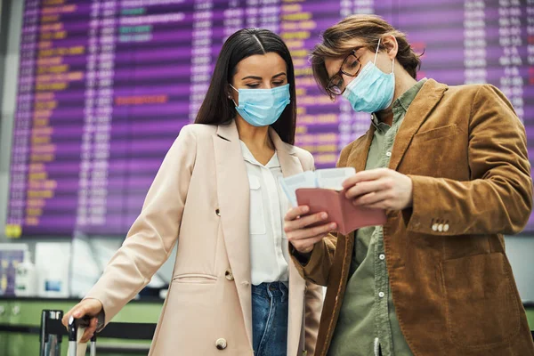 Orvosi maszkos férfi és nő a repülőtéren ellenőrzik a jegyeket. — Stock Fotó