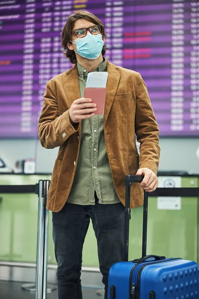 Férfi utazó orvosi maszkban várja a repülést a repülőtéren — Stock Fotó