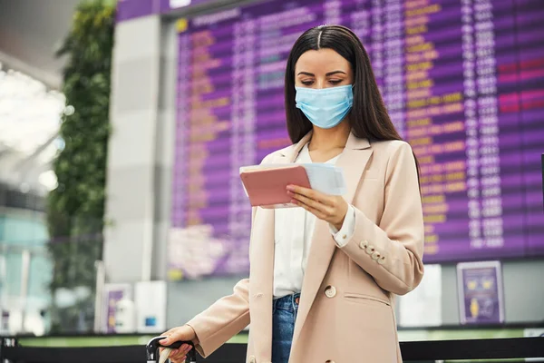 의료용 마스크를 착용하고 공항에서 비행기를 기다리는 여성 여행자 — 스톡 사진