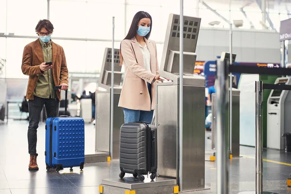 Passageiros que utilizam a máquina de pesagem de bagagem no aeroporto — Fotografia de Stock