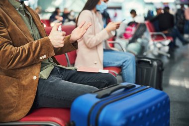 Havalimanında el dezenfektanı kullanan şık bir genç.