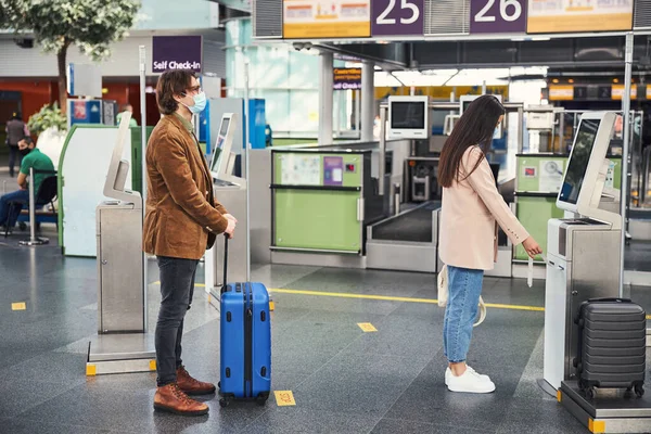 Pasajeros que utilizan la máquina de pesaje de control de equipaje en la terminal del aeropuerto —  Fotos de Stock