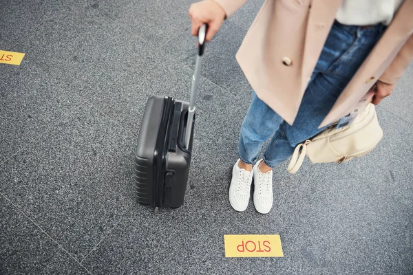 여행 가방을 들고 공항에서 노란색 정지 표지판을 들고 있는 여자 — 스톡 사진