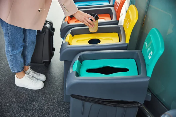Vrouwelijke passagier gooit koffiebeker in vuilnisbak op het vliegveld — Stockfoto