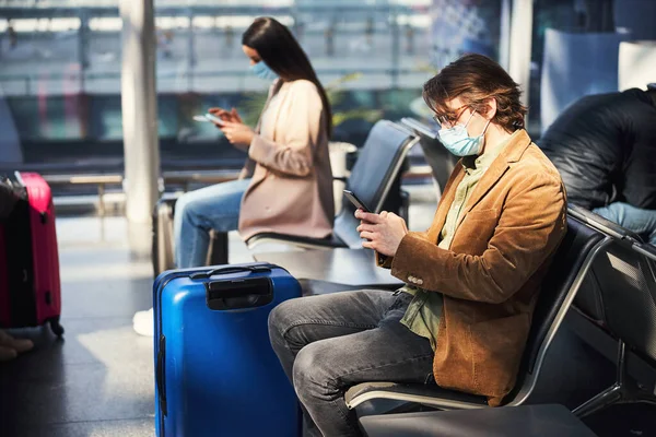空港でスマートフォンを使用した医療用マスクのスタイリッシュな男 — ストック写真