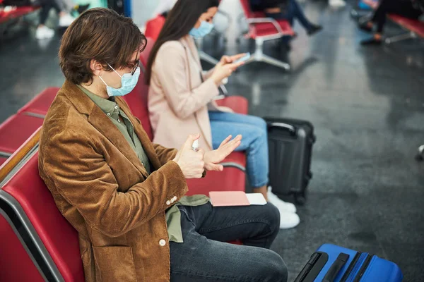 空港で手の消毒剤を使用した医療用マスクのスタイリッシュな男 — ストック写真