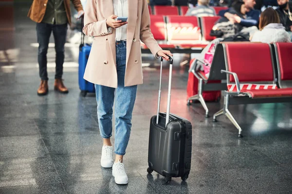 Элегантная молодая женщина с мобильным телефоном в аэропорту — стоковое фото