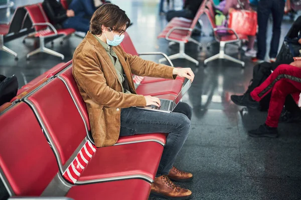 空港でラップトップを使用した医療用マスクのスタイリッシュな男 — ストック写真