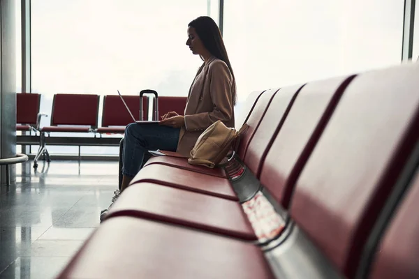 विमानतळावर लॅपटॉप वापरून आकर्षक तरुण स्त्री — स्टॉक फोटो, इमेज