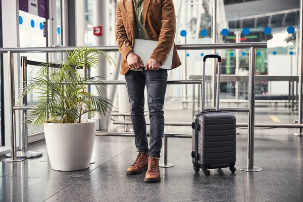 Elegante hombre con portátil moderno de pie en el aeropuerto —  Fotos de Stock
