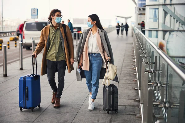 空港で屋外を歩く医療用マスクの素敵なカップル — ストック写真