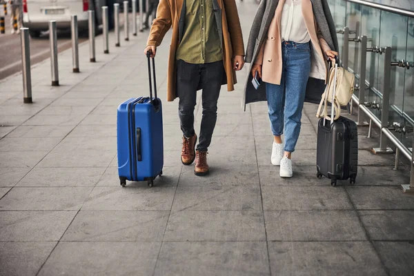 Pareja joven con maletas de viaje caminando al aire libre en el aeropuerto —  Fotos de Stock