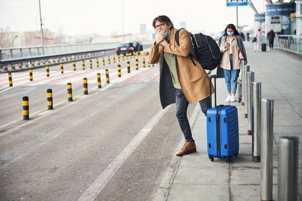 ストリートでタクシーをキャッチ旅行スーツケースを持つスタイリッシュな男 — ストック写真