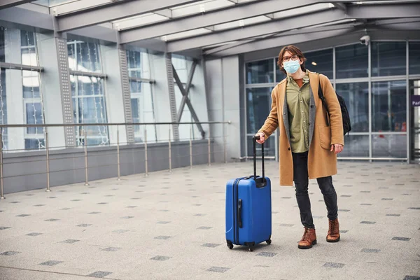 空港ターミナルに立つ医療用マスクのスタイリッシュな男 — ストック写真