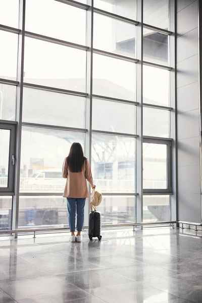 Κομψή γυναίκα με ταξιδιωτική βαλίτσα στέκεται στο αεροδρόμιο τερματικό — Φωτογραφία Αρχείου