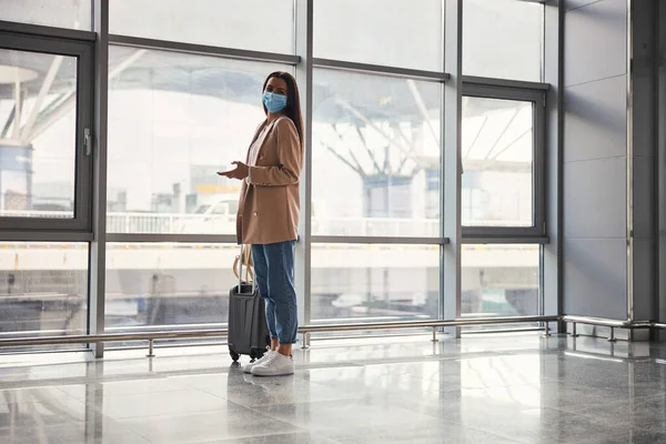 空港ターミナルに立つ医療マスクの魅力的な女性 — ストック写真