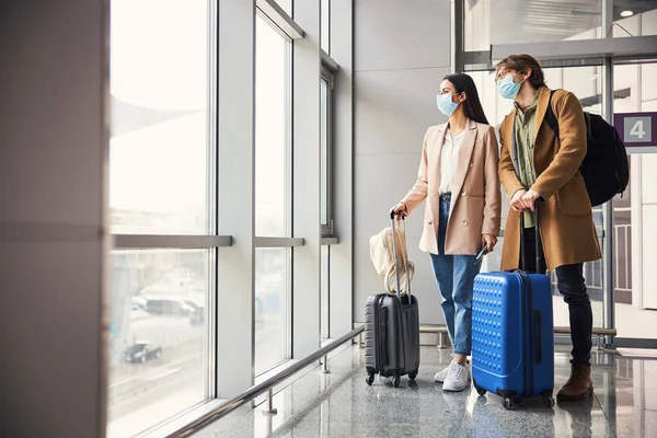 공항 터미널에서 있는 의료용 마스크를 쓴 사랑 스런 부부 — 스톡 사진