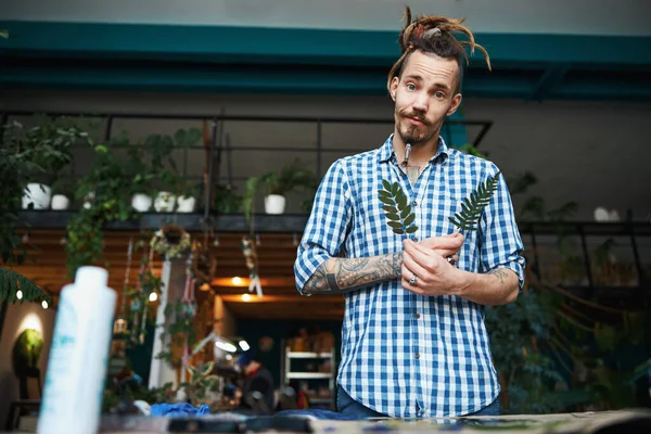 Knappe jongeman met planten in de werkplaats — Stockfoto