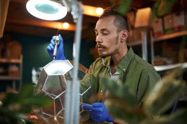 Atölyede cam floraryum yapan yakışıklı genç adam.