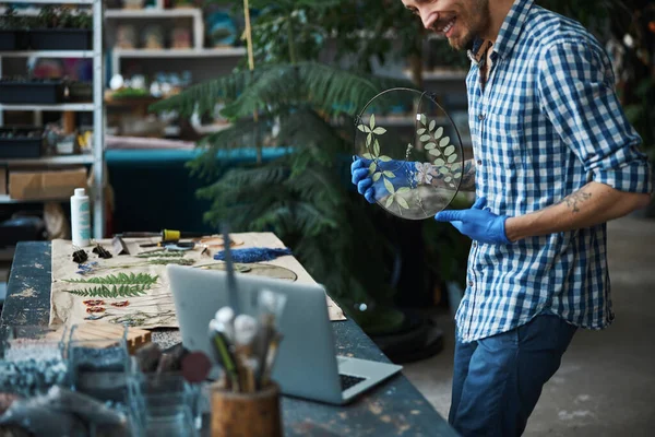 Vrolijke mannelijke kruidendokter met herbarium en laptop — Stockfoto