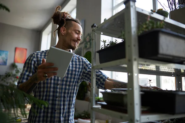 Knappe man die digitale tabletcomputer gebruikt en planten controleert — Stockfoto