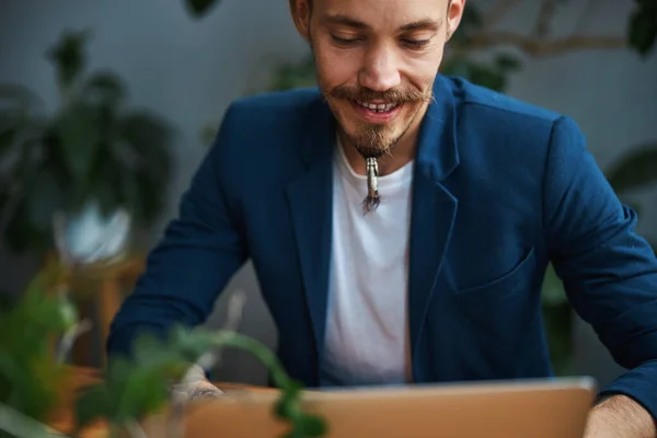 Fröhlicher bärtiger Mann arbeitet im Büro am Laptop — Stockfoto
