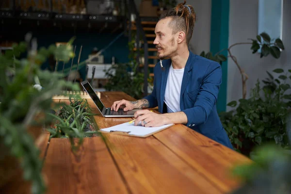 Glada ung man som använder laptop på jobbet — Stockfoto