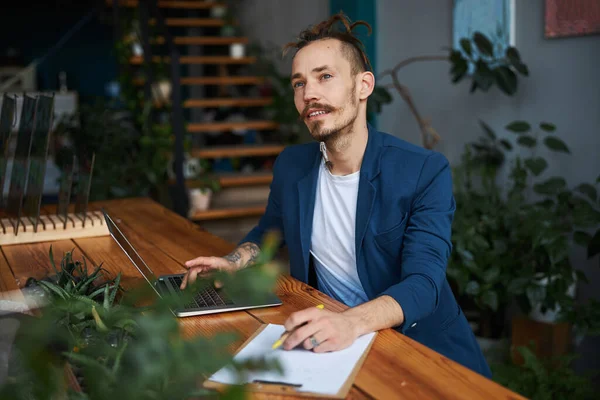 Beau jeune homme utilisant un ordinateur portable au travail — Photo