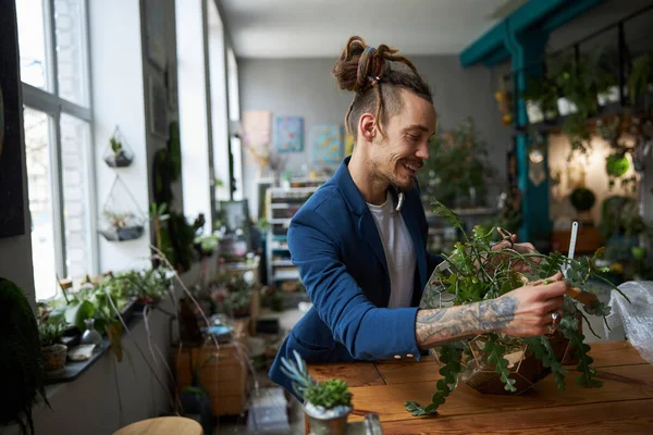 Vreugdevolle jongeman schoonmaken plant bladeren met borstel — Stockfoto