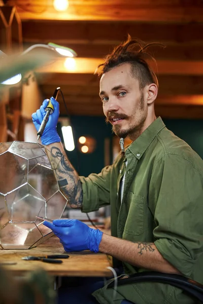 Vreugdevolle jongeman die glazen florarium maakt in de werkplaats — Stockfoto