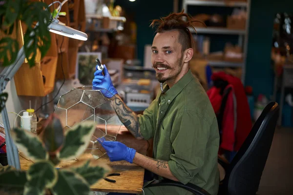 Vrolijke jongeman maakt glazen terrarium in werkplaats — Stockfoto