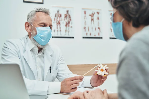 Médico explicando o básico da anatomia da coluna vertebral durante a consulta ao paciente — Fotografia de Stock