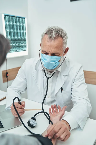 Médico concentrado midiendo la tensión arterial del paciente — Foto de Stock