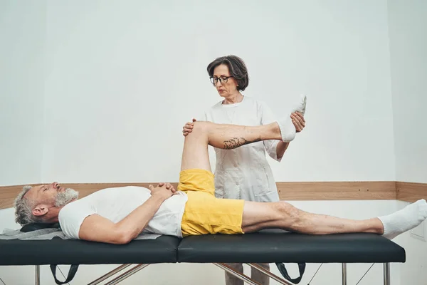 Lady doctor performing a hip joint resisted isometric test — Stock Photo, Image