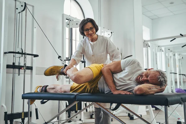 Man doing a lateral leg raise assisted by a doctor — Stock Photo, Image