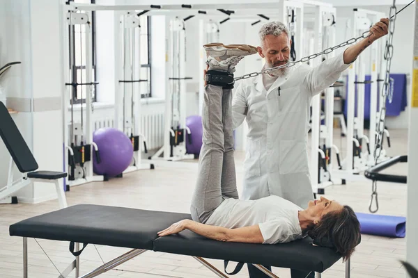 Woman performing a strength training exercise assisted by a kinesiologist — Stock Photo, Image