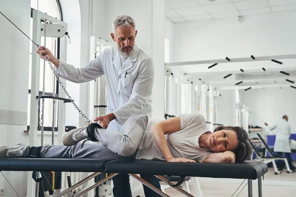 Doctor rehabilitating a patient after the leg injury — Stock Photo, Image